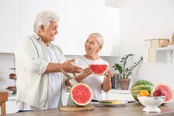 Mature couple with cut watermelon in kitchen
