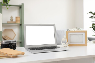 Blank laptop with frame and photo camera on desk in living room, closeup