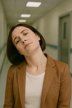 A woman with cervical dystonia (spasmodic torticollis)stands in a hallway, showing visible discomfort due to involuntary neck muscle contractions.