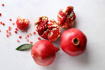 Fresh ripe pomegranates with seeds and leaf on light background