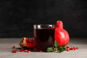 Glass of fresh pomegranate juice and seeds on white table