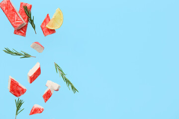 Cut tasty crab sticks with rosemary and slice of lemon flying on blue background © Pixel-Shot