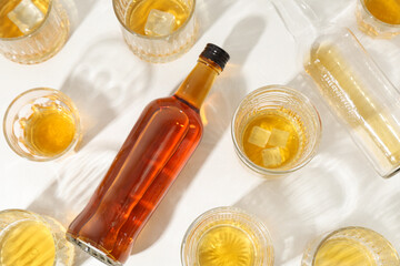 Bottles and glasses of cold rum on white background