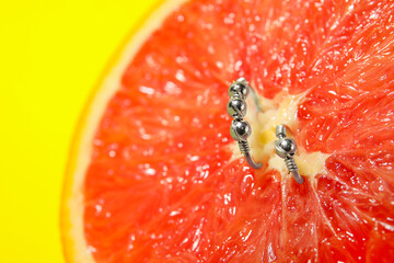 Half of grapefruit with piercing on yellow background, closeup