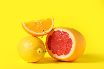 Citrus fruits with piercing on yellow background