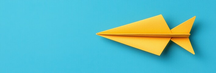 Vibrant Yellow Paper Airplane Resting on a Bright Blue Background Evoking Creativity and Playfulness