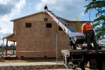 Heavy duty work truck with conveyer belt boom arm delivering roofing materials to a residential...