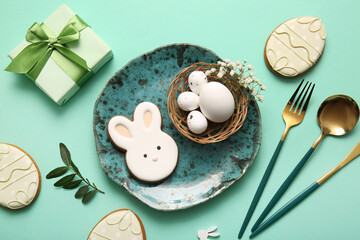 Beautiful table setting with sweet cookies, Easter eggs, gift box and gypsophila flowers on turquoise background