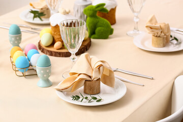 Festive Easter table setting with painted eggs, Easter cake and green bunny. Closeup