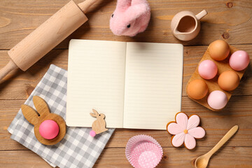 Composition with blank recipe book, kitchen utensils and Easter eggs on wooden background