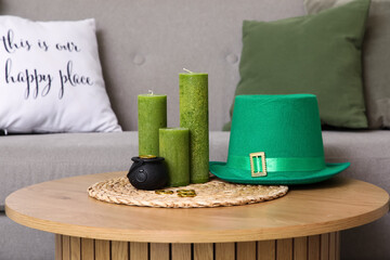 Leprechaun's hat with pot and candles on table in room decorated for St. Patrick's Day, closeup