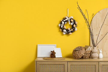 Chest of drawers near yellow wall in room decorated for Easter celebration