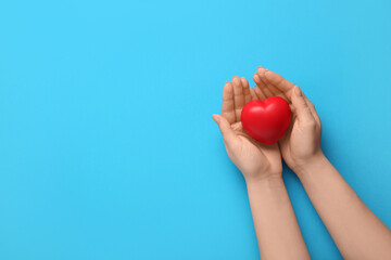 Female hands with heart on blue background. World Health Day