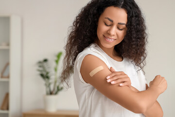 Young African-American woman with medical patch after vaccination at home