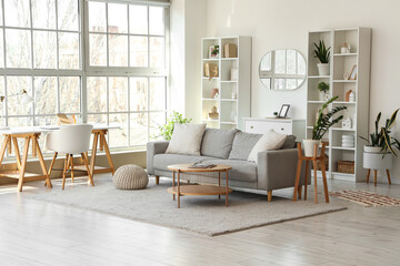 Interior of light living room with grey sofa, workplace and mirror