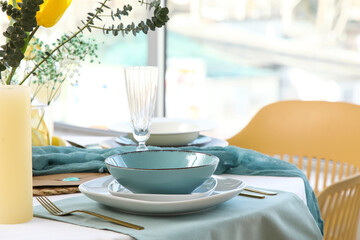 Elegant table setting with golden cutlery, clean plates and eucalyptus branches in restaurant