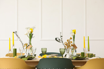 Table setting with spring flowers near light wall in room