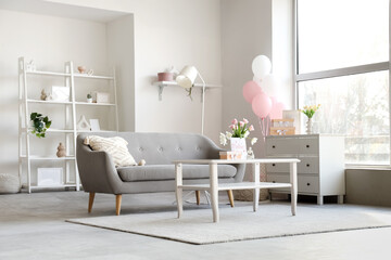 Interior of light living room decorated for Mother's Day with sofa, table and balloons