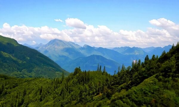 Green mountains beneath a bright blue sky with scattered clouds on a sunny summer day