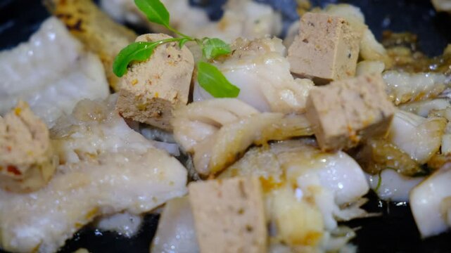 Cooking Indoors pan grilled seasoned Cod fillets and Tofu with spices and sun-dried tomatoes. On Stovetop, iron cast skillet, close up boiled oil, process deep fried.