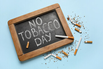 Chalkboard with text NO TOBACCO DAY and cigarette butts on blue background