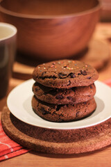 Handmade cookies with chocolate chips on a white plate and fresh milk in a glass. Selective focus