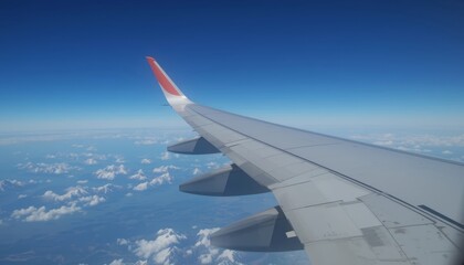 Obraz premium Airplane wing flying above the clouds against a clear blue sky 