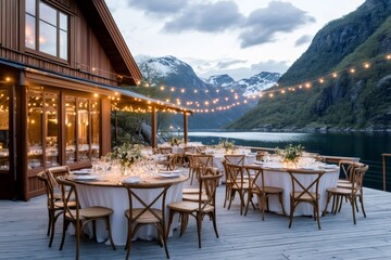 Obraz premium Outdoor wedding reception venue overlooking a fjord in Norway with string lights illuminating round tables