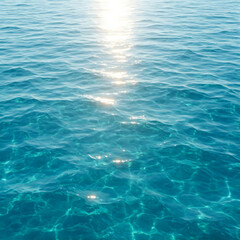 Obraz premium A serene view of the ocean's surface with the sun reflecting on the calm water, showcasing clear blue waves and the peaceful beauty of the sea.