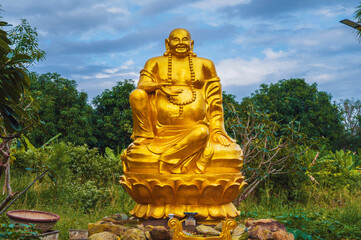 Obraz premium Golden Buddha statue surrounded by tropical plants in a garden in Asia.