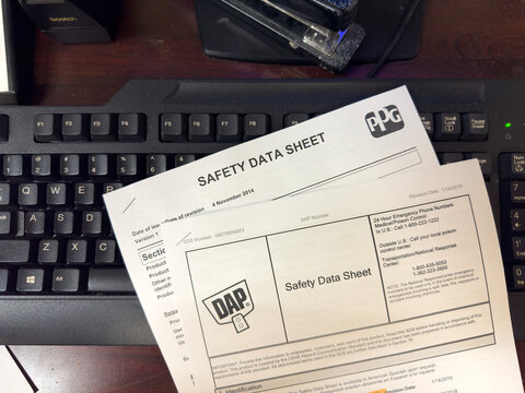 Freshly printed Safety Data Sheets on office keyboard.