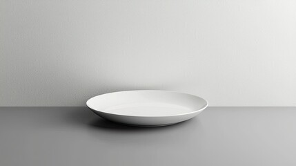 A single white plate placed on a gray surface is shown