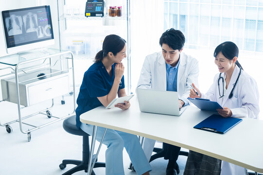 Multidisciplinary Medical Team Planning Treatment in Office
Three healthcare workers in a medical office setting are engaged in a friendly discussion around a laptop, preparing a treatment
