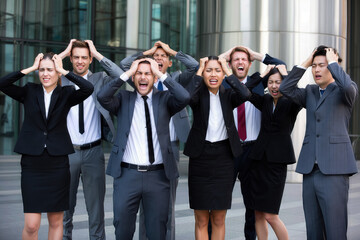 Fototapeta premium Diverse group of stressed young adults in business attire expressing frustration outdoors