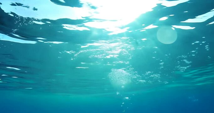 Blue water splash with waves under a clear sky and sunlight, reflecting the ocean's beauty in a serene seascape