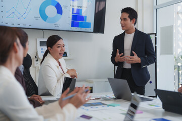 Business team collaborating on project in modern office, analyzing charts and graphs on a large screen during a productive meeting led by an asian businessman
