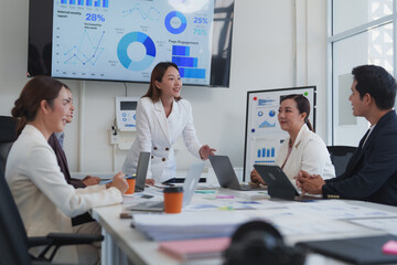 Asian entrepreneurs engaging in a dynamic office meeting, discussing company performance while analyzing charts and statistics on screens and projectors, fostering collaboration and strategy