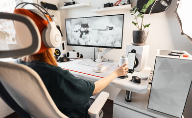 Gamer extends hand to grab sleek white energy drink can while gaming. Stylish desk setup with...