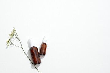 Refined amber vials paired with tiny white buds symbolize organic beauty routine, organic statement of authenticity, organic choice elevating brand identity and eco-forward vision