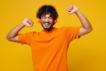 Young smiling cheerful happy Indian man he wear orange t-shirt casual clothes listen to music in...