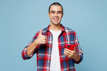 Young happy middle eastern man he wear red shirt casual clothes hold in hand use mobile cell phone...