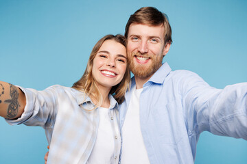 Obraz premium Close up young couple two friends family man woman wear shirt casual clothes together doing selfie shot pov on mobile cell phone isolated on pastel plain blue cyan background studio Lifestyle concept