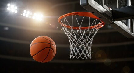 A basketball near a hoop with stadium lighting in the background ready for a game to start soon