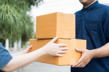 Delivery man holding cardboard boxes. Hand female accepting a delivery boxes of paper containers from courier at home. Signing to get package. Delivery concept.