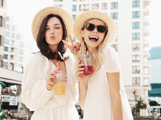Two young beautiful smiling hipster female in trendy summer white dress and straw hats. Sexy...