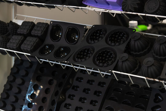 Various silicone molds are neatly organized on metal shelves in a workshop.