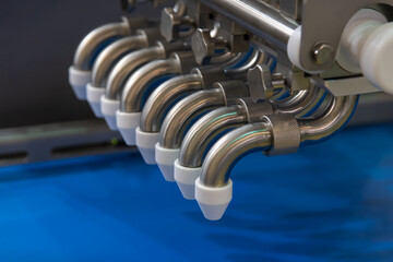 Industrial machinery with multiple metallic nozzles applies precise coatings onto materials.