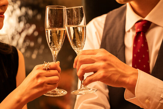 Detailed close-up shot of two champagne flutes clinking together during a toast at an elegant bar. The hands, jewellery, and bubbles emphasize sophistication and celebration.