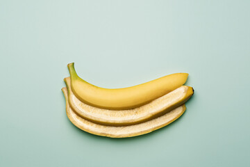 Lengthwise cut banana in three slices rests on pastel mint background, exuding fresh tropical taste...