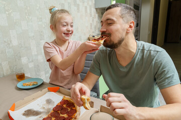 Happy father and daughter eating the delicious pizza at home